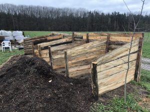 Ein Sammelbehälter aus Holz für Gartenabfälle und Kompost mit mehreren getrennten Abteilen.